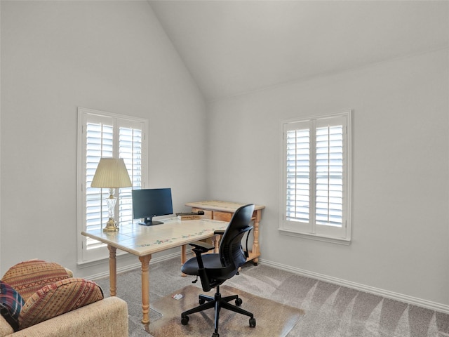 office featuring vaulted ceiling, a healthy amount of sunlight, baseboards, and light carpet