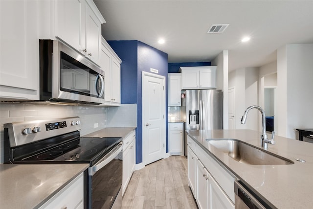 kitchen with tasteful backsplash, visible vents, appliances with stainless steel finishes, light wood-type flooring, and a sink