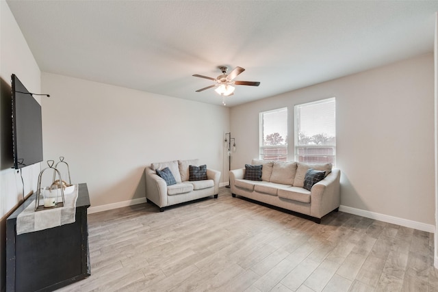 living room with light wood-style floors, ceiling fan, and baseboards