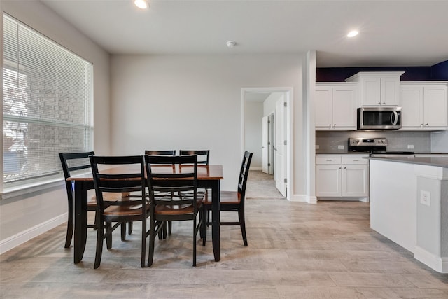 dining room with light wood finished floors, plenty of natural light, baseboards, and recessed lighting