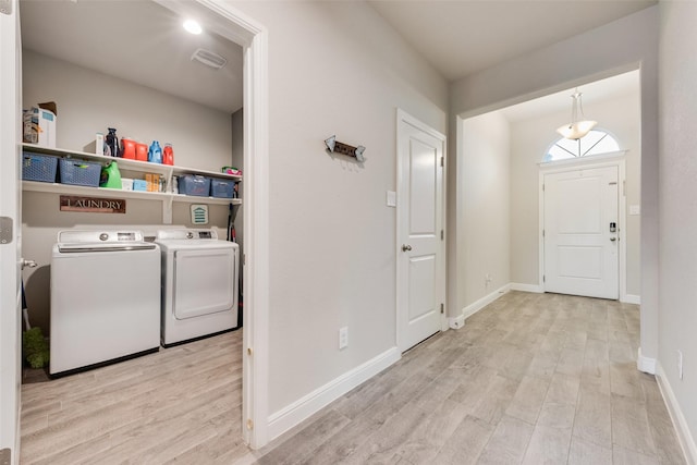 laundry room with laundry area, baseboards, light wood finished floors, and washing machine and clothes dryer