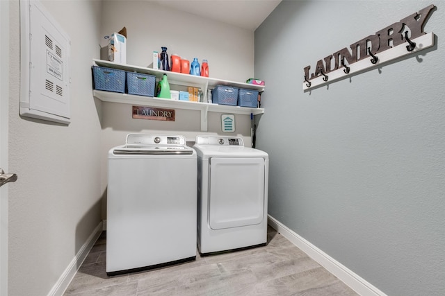 laundry area featuring laundry area, baseboards, electric panel, light wood finished floors, and washing machine and clothes dryer