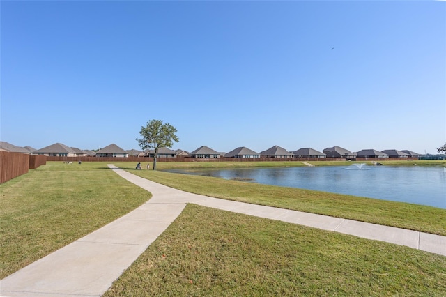 view of community with a water view, a residential view, fence, and a lawn