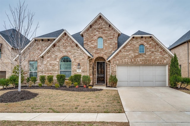 french provincial home featuring brick siding, a shingled roof, concrete driveway, an attached garage, and a front lawn