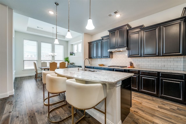 kitchen featuring light stone counters, dark wood-type flooring, a sink, and backsplash