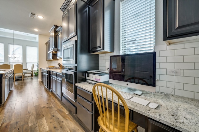 kitchen featuring visible vents, appliances with stainless steel finishes, wood finished floors, light stone countertops, and backsplash