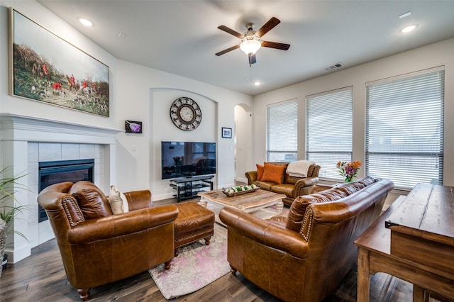 living room featuring arched walkways, recessed lighting, a fireplace, wood finished floors, and visible vents