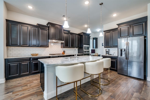 kitchen featuring wood-type flooring, visible vents, appliances with stainless steel finishes, a sink, and under cabinet range hood