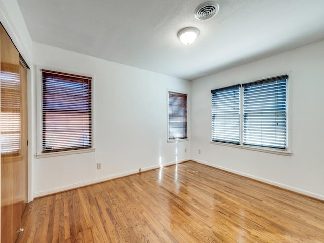 unfurnished room featuring wood finished floors, visible vents, and baseboards