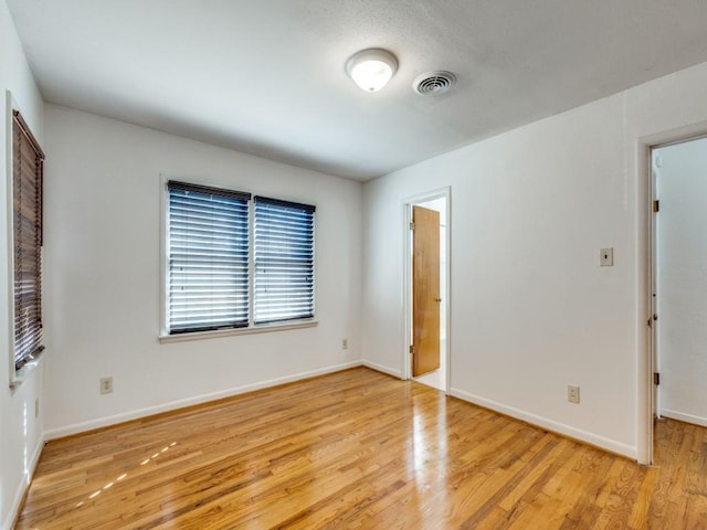 unfurnished room featuring light wood finished floors, baseboards, and visible vents