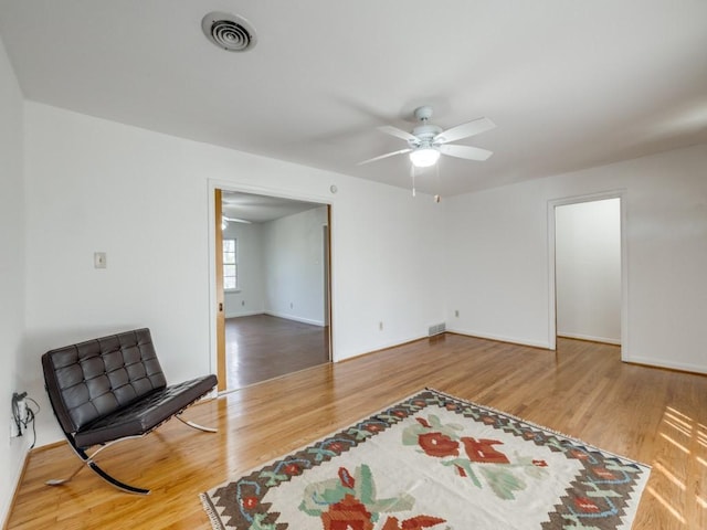 living area featuring wood finished floors, visible vents, and a ceiling fan