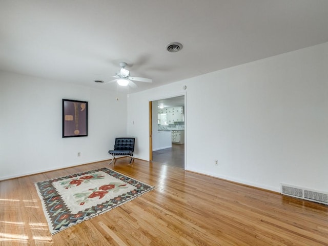 unfurnished room featuring a ceiling fan, visible vents, baseboards, and wood finished floors