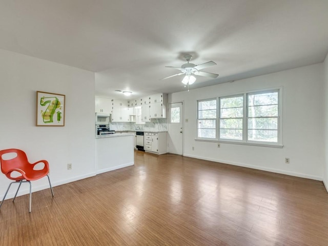 unfurnished living room featuring a ceiling fan, baseboards, and wood finished floors