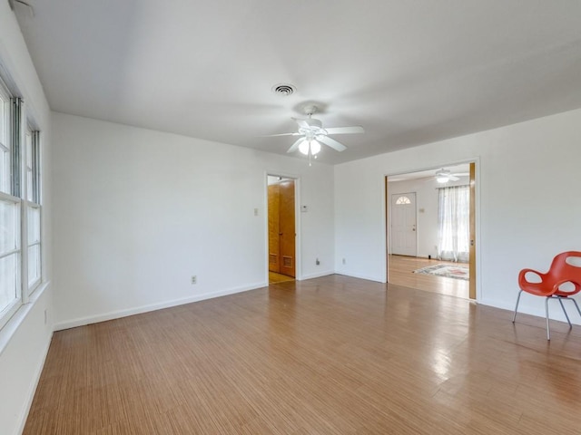 spare room with a ceiling fan, wood finished floors, visible vents, and baseboards