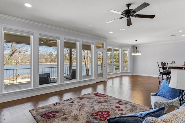 living area with a water view, hardwood / wood-style flooring, crown molding, and ceiling fan with notable chandelier