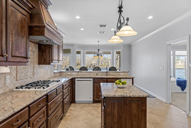 kitchen featuring gas stovetop, visible vents, stainless steel dishwasher, a sink, and premium range hood