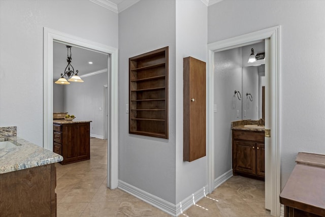 hall featuring baseboards, crown molding, a sink, and light tile patterned floors