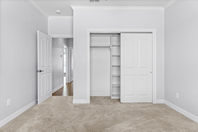 unfurnished bedroom featuring a closet, ornamental molding, and carpet flooring