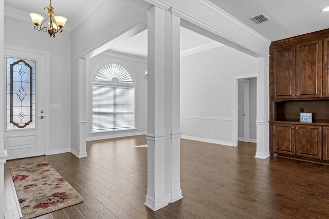 entryway featuring decorative columns, visible vents, dark wood-type flooring, ornamental molding, and a chandelier