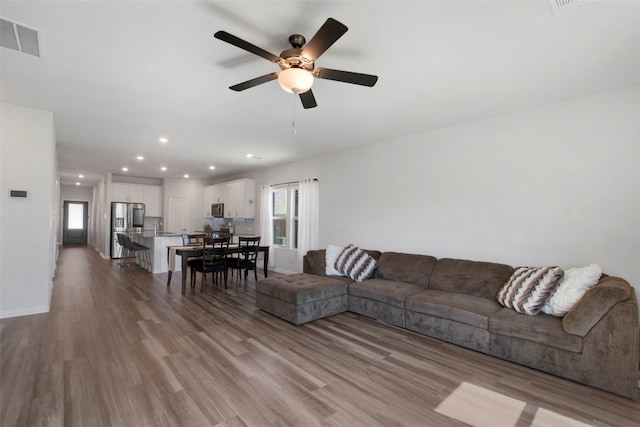 living area featuring recessed lighting, visible vents, a ceiling fan, wood finished floors, and baseboards