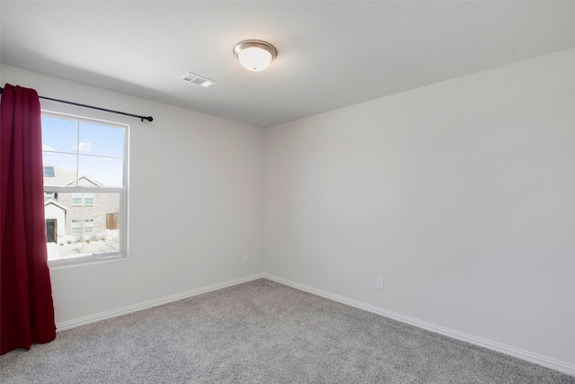 carpeted spare room with visible vents and baseboards