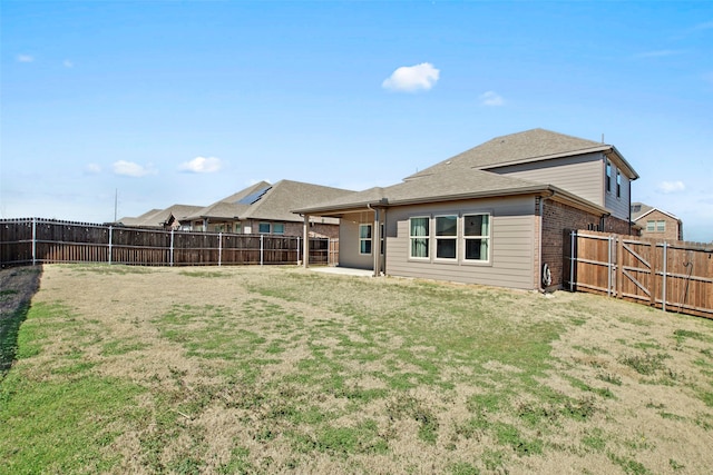 rear view of property with a patio, brick siding, a lawn, and a fenced backyard