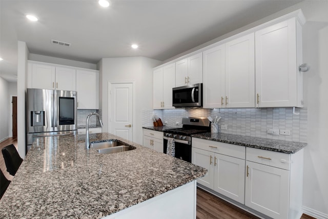 kitchen featuring stainless steel appliances, a sink, visible vents, white cabinetry, and dark wood finished floors