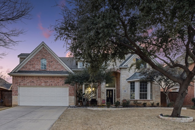 view of front of home with stone siding, fence, concrete driveway, and brick siding