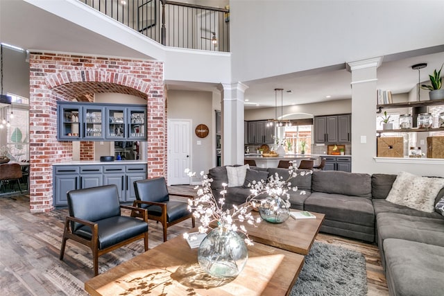 living room with a towering ceiling, wood finished floors, and decorative columns