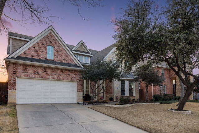 traditional-style house with a garage, concrete driveway, brick siding, and stone siding