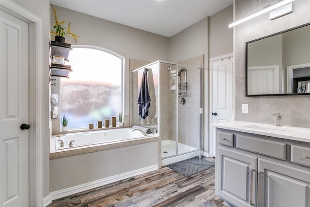 full bathroom featuring a garden tub, wood finished floors, a shower stall, and vanity