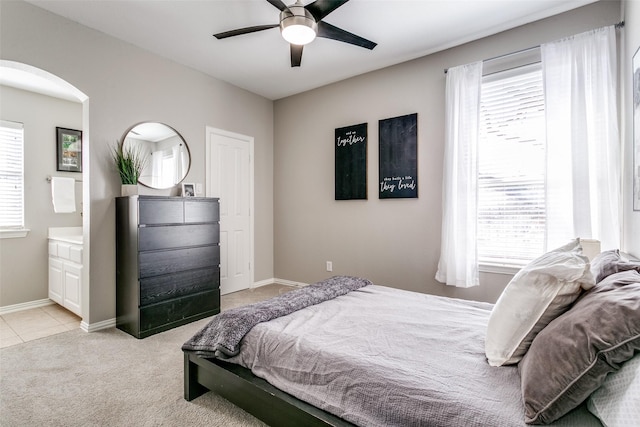 bedroom featuring arched walkways, multiple windows, light carpet, and baseboards