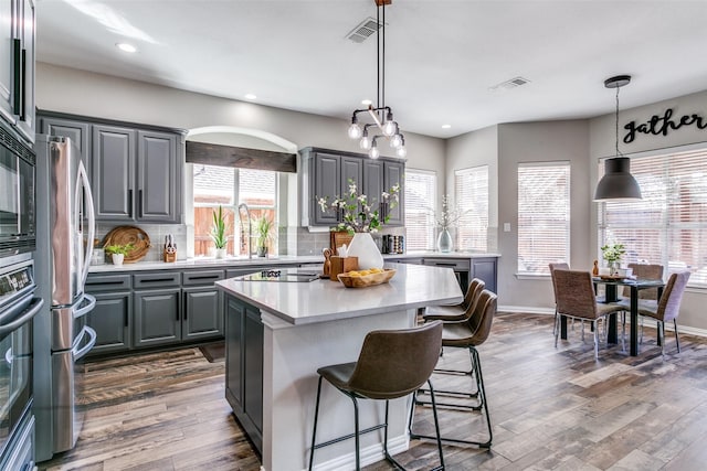 905 Water Oak Dr, Grapevine, TX 76051 - kitchen featuring gray cabinets, light countertops, a kitchen breakfast bar, backsplash, and dark wood-style floors