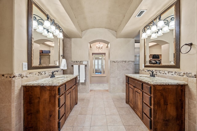 bathroom featuring tile walls, visible vents, and a sink