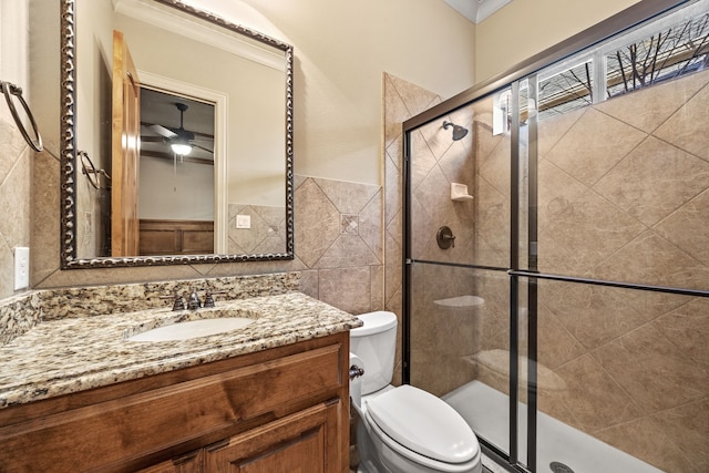 full bathroom with a shower stall, tile walls, vanity, and toilet