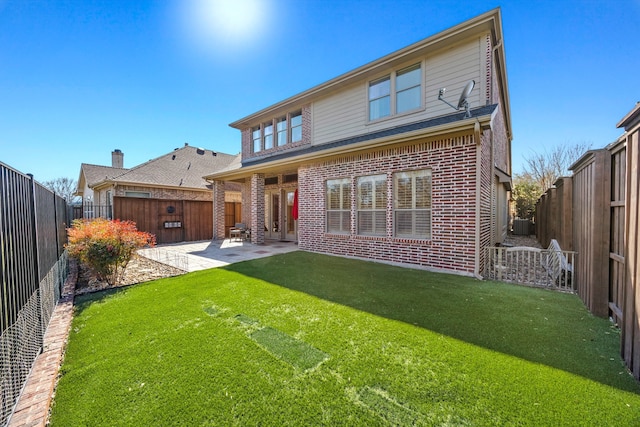 rear view of house with brick siding, a fenced backyard, a lawn, and a patio