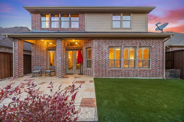 back of house with brick siding, a patio area, a yard, and fence