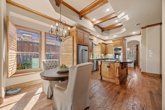 kitchen with visible vents, a kitchen island, wood finished floors, stainless steel appliances, and arched walkways