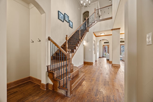 entryway featuring a high ceiling, wood finished floors, arched walkways, and baseboards