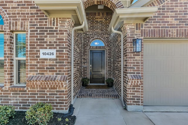 property entrance featuring brick siding and an attached garage