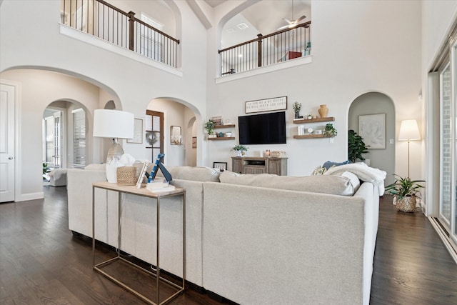 living room with dark wood-type flooring, a towering ceiling, and baseboards