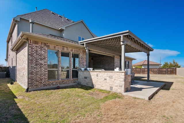 back of property with a patio area, a shingled roof, fence, and brick siding