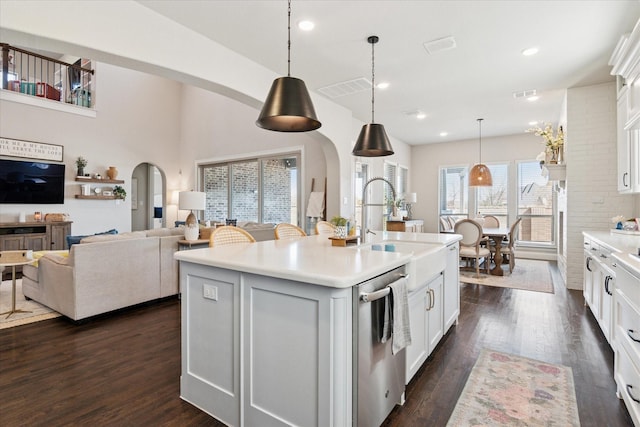 kitchen featuring arched walkways, dark wood-type flooring, a sink, light countertops, and dishwasher