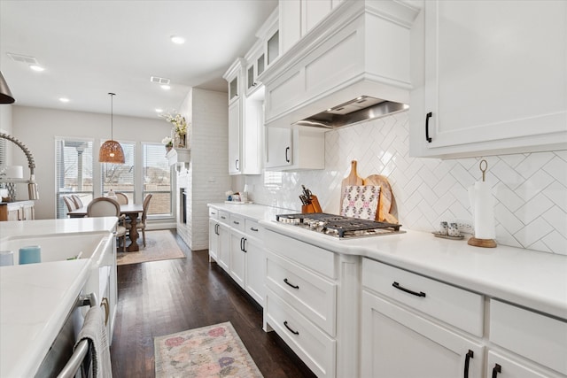 kitchen with stainless steel gas stovetop, custom exhaust hood, white cabinets, and light countertops