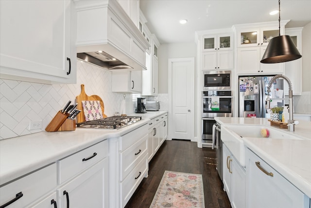 kitchen with stainless steel appliances, light countertops, dark wood-type flooring, white cabinetry, and premium range hood