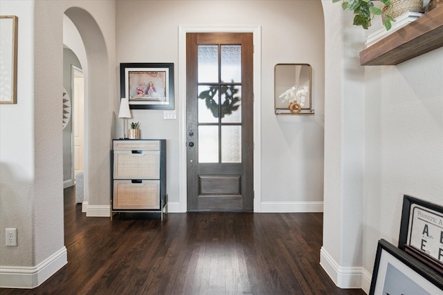 entrance foyer featuring dark wood-style floors, baseboards, and arched walkways