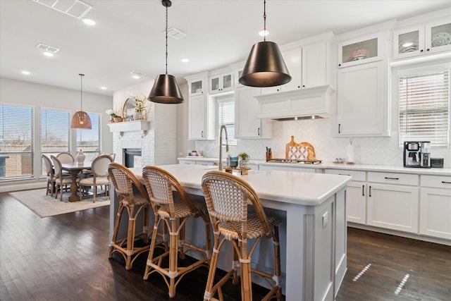 kitchen with dark wood-style floors, light countertops, a kitchen island with sink, and custom exhaust hood