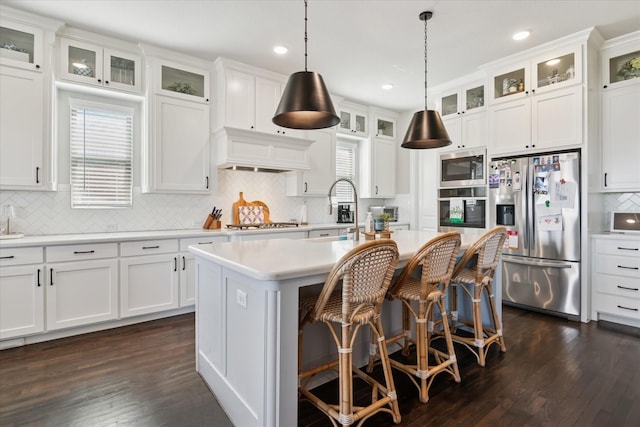 kitchen featuring a center island with sink, appliances with stainless steel finishes, light countertops, premium range hood, and white cabinetry