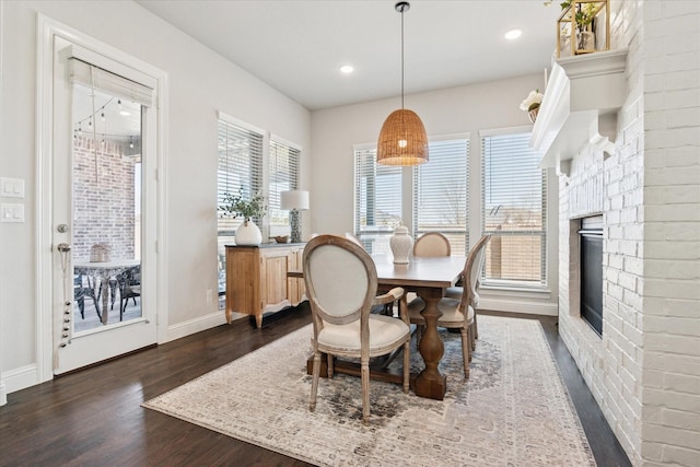 dining area featuring a wealth of natural light, a fireplace, dark wood finished floors, and baseboards