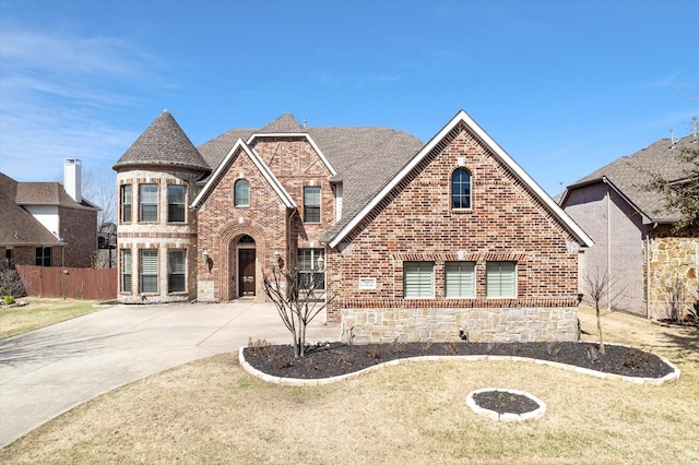 view of front of house with brick siding, fence, concrete driveway, a front yard, and roof with shingles